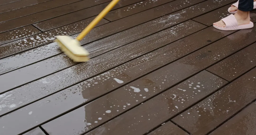 A person scrubbing a composite deck with a brush